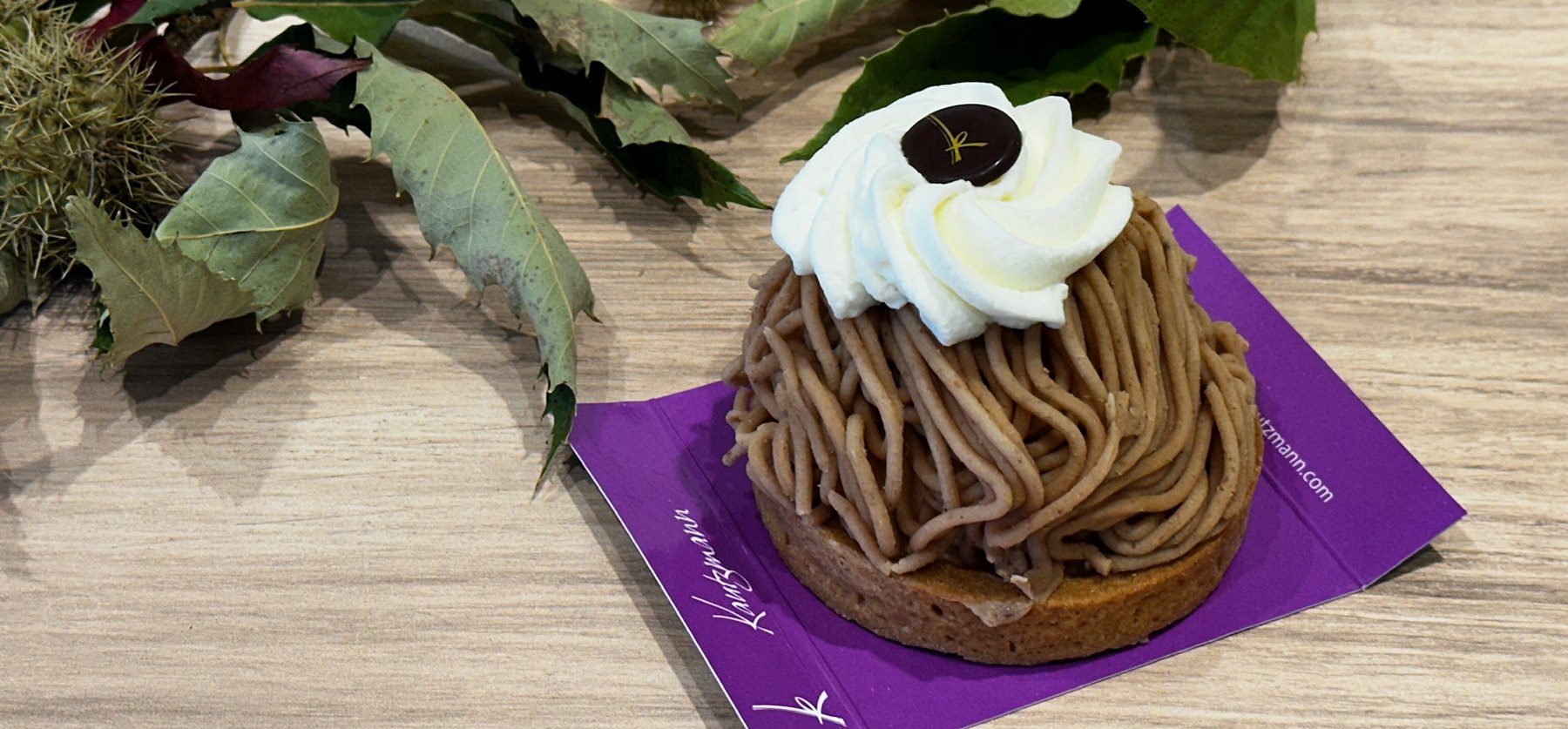 Torche aux marrons de la Pâtisserie Kautzmann sur son carton violet, entière, avec des feuilles et des bogues de châtaignier