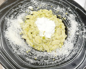 Gnocchis au pesto de pistache, cœur de stracciatella et parmesan, servis dans une assiette noire