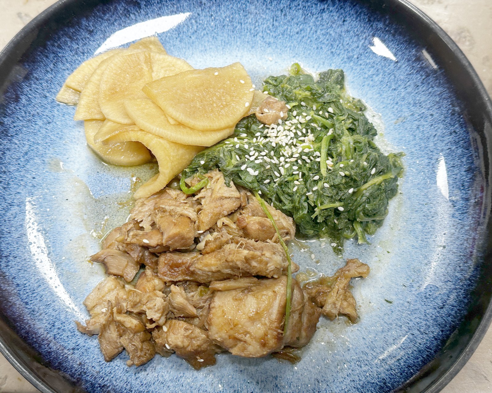 Poitrine de porc braisée façon kakuni, radis blanc et épinards au sésame, dans une assiette bleue